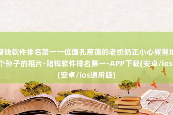 赌钱软件排名第一一位面孔慈蔼的老奶奶正小心翼翼地捧着两个孙子的相片-赌钱软件排名第一-APP下载(安卓/ios通用版)